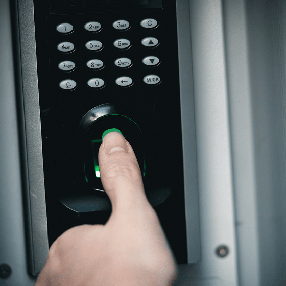 Eine Hand drückt auf einen Fingerabdruckscanner an einem Kontrollpanel mit Tasten.